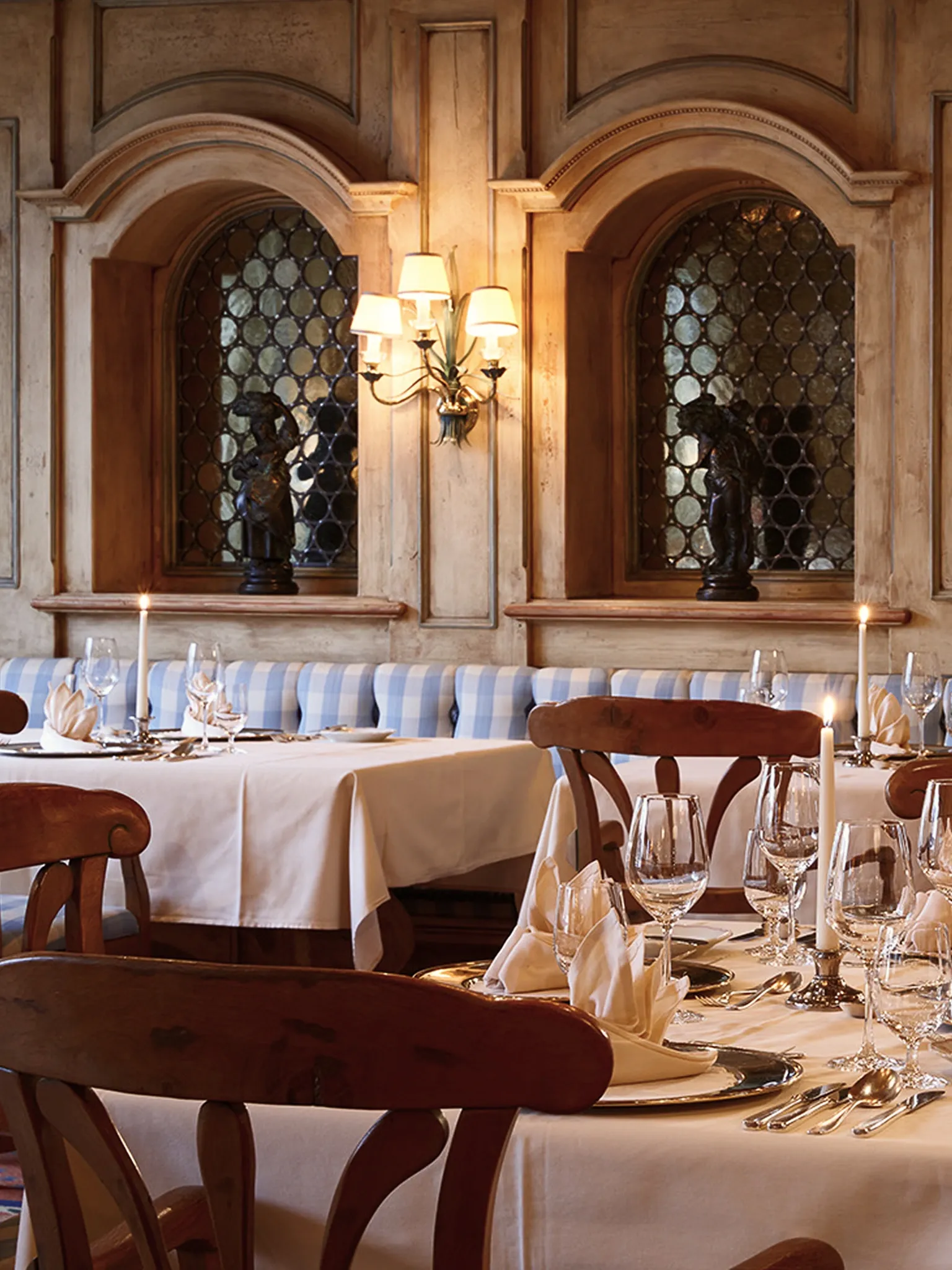 Restaurantsaal mit Rundbogenfenstern, Holzstühlen und weiß eingedeckten Tischen.
