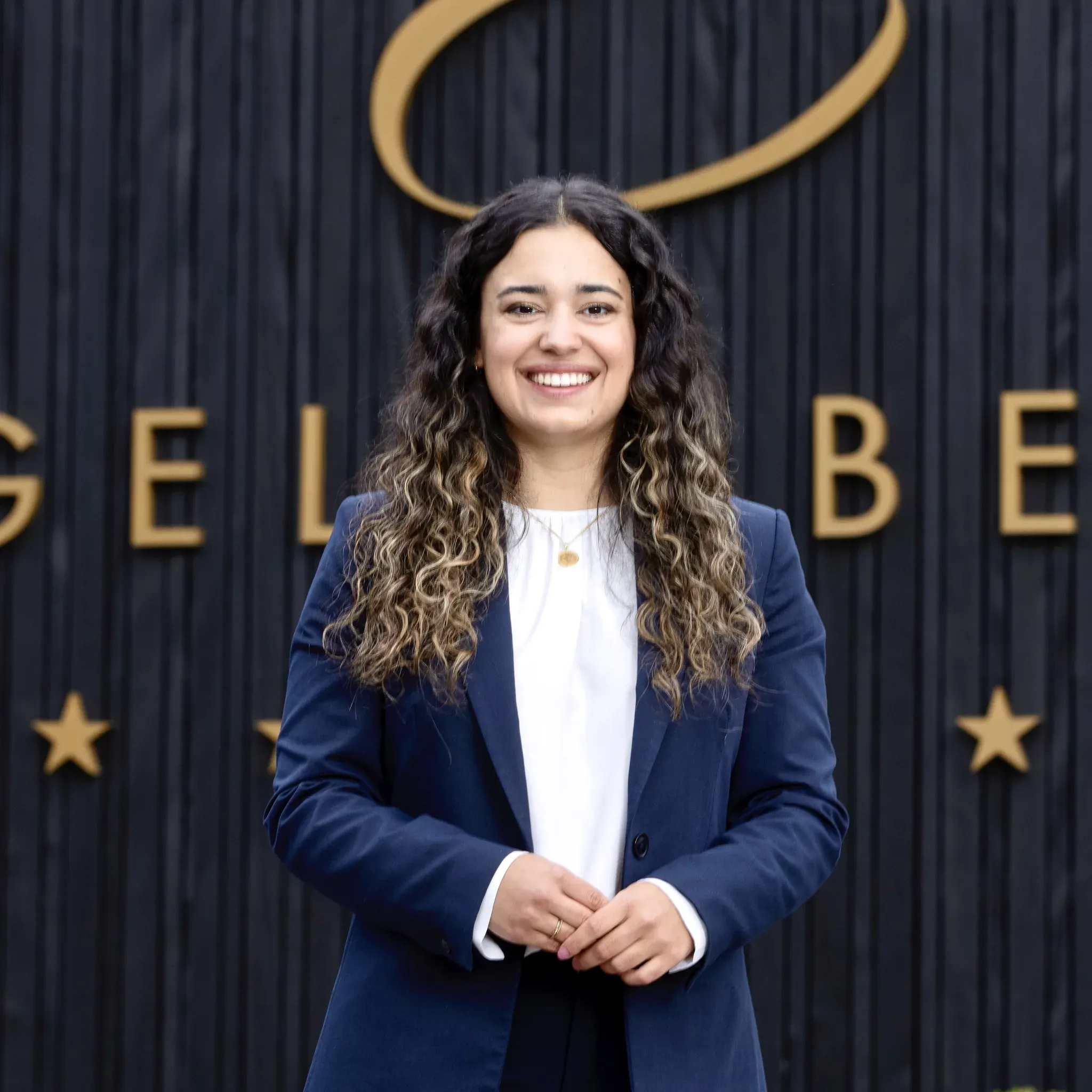 Porträt von Nadine Haier, stellvertretende Hoteldirektorin im Engel Obertal, vor dunkler Holzwand mit goldenem Schriftzug.