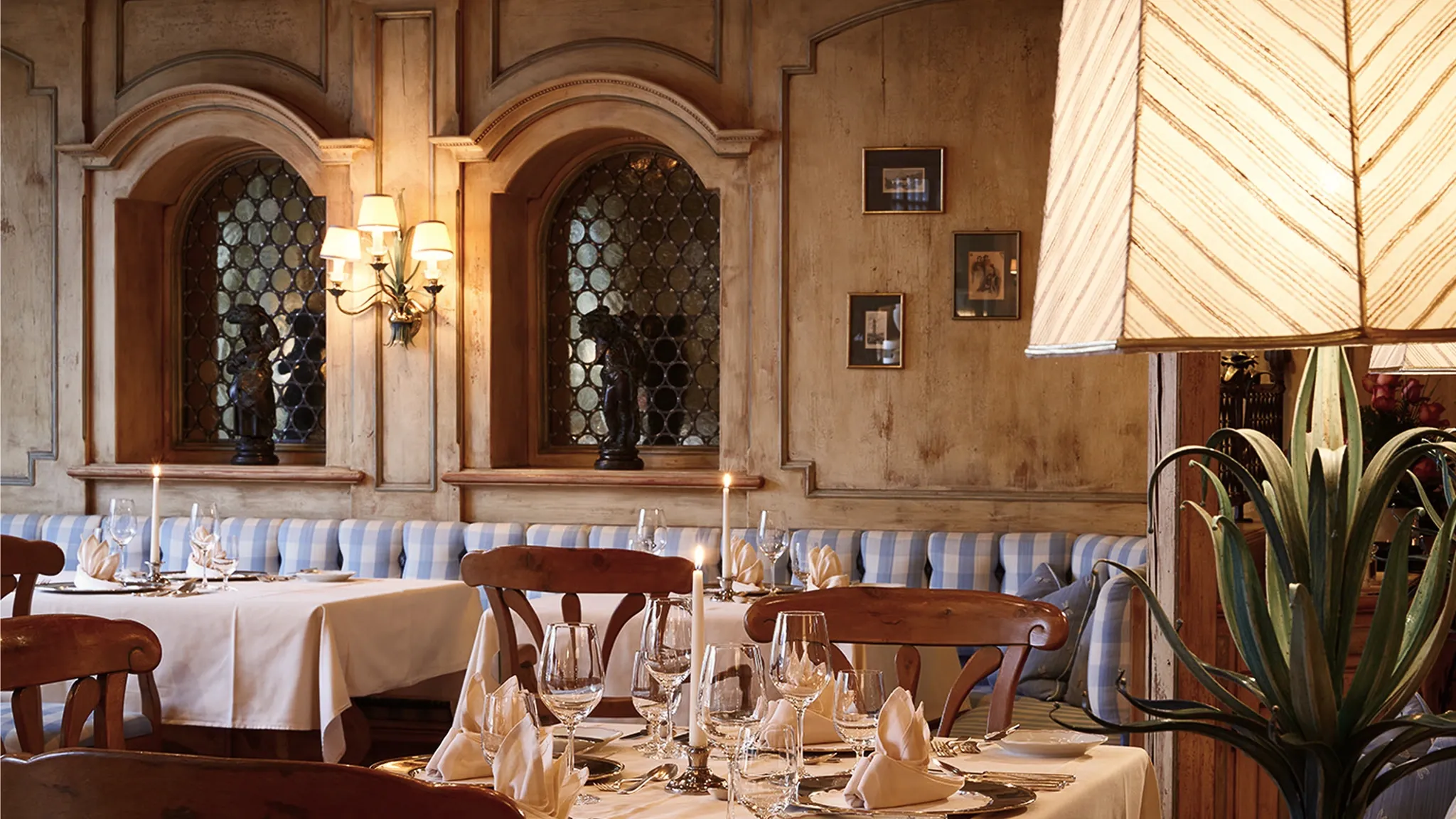 Restaurantsaal mit Rundbogenfenstern, Holzstühlen und weiß eingedeckten Tischen.