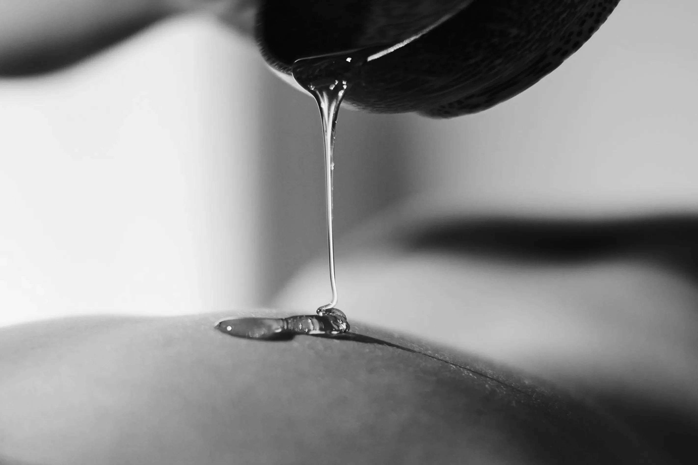 Massageöl wird aus einer Schale auf einen Rücken gegossen, Schwarz-Weiß-Aufnahme